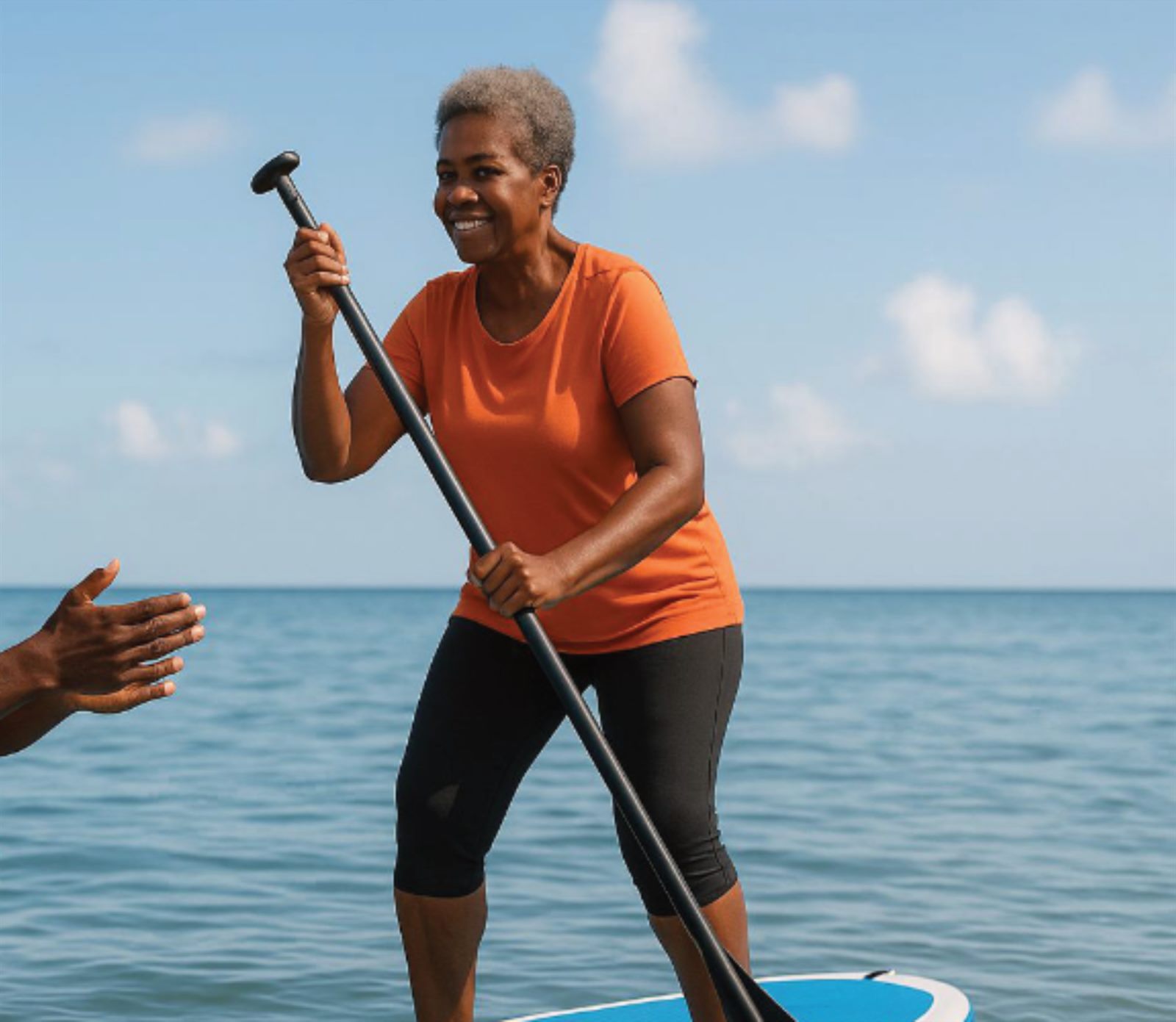 Une pratiquante debout, pagaie en main, face à la mer