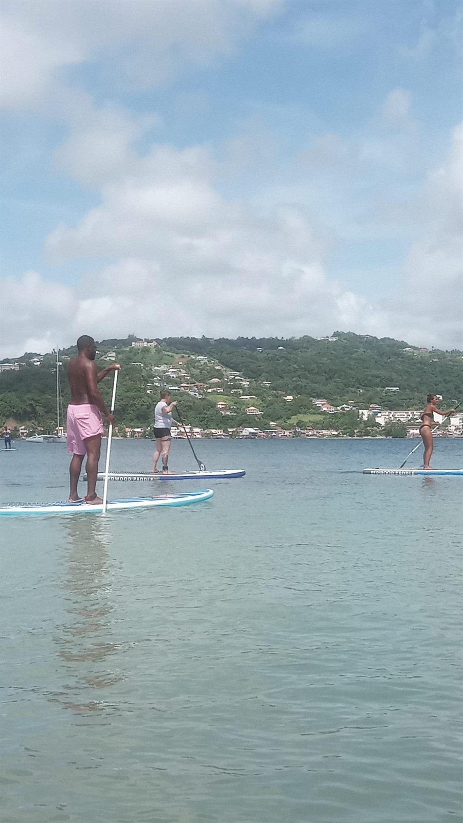 Trois pratiquants debout sur leurs planches, face aux collines