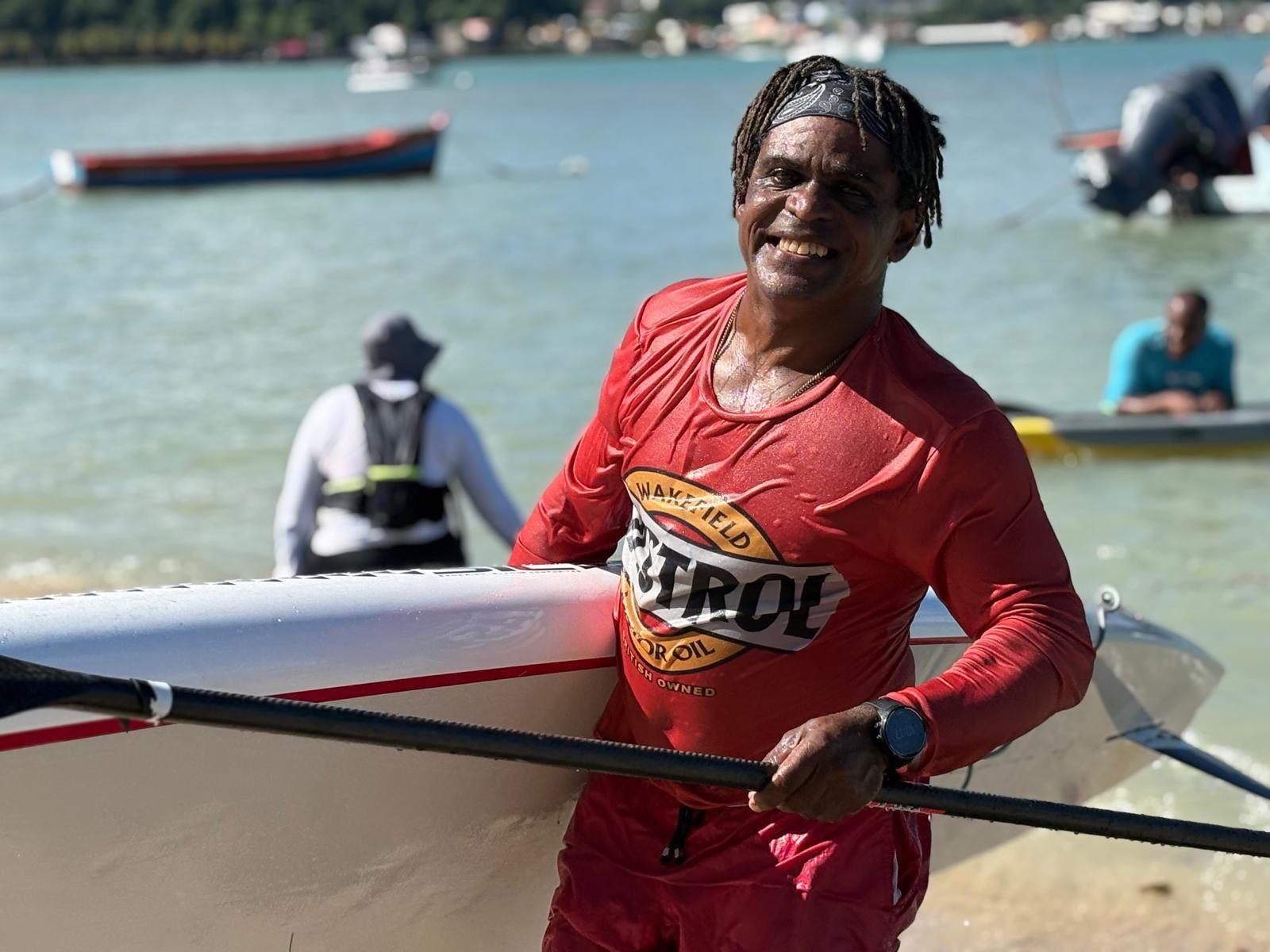 Sourire en sortant de l'eau, planche sous le bras